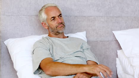 Man-sitting-in-his-bed-while-watching-television