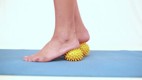 Girl-using-yellow-massage-balls-on-her-feet