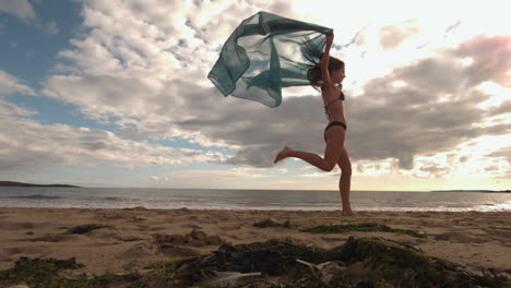 Woman-bouncing-at-the-beach-holding-a-scarf