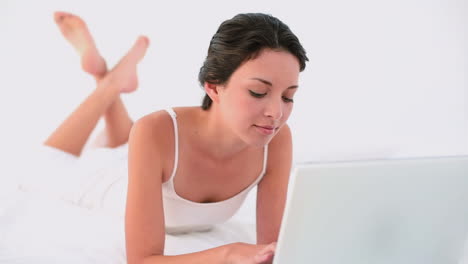 Thoughtful-brunette-using-her-laptop-and-smiling