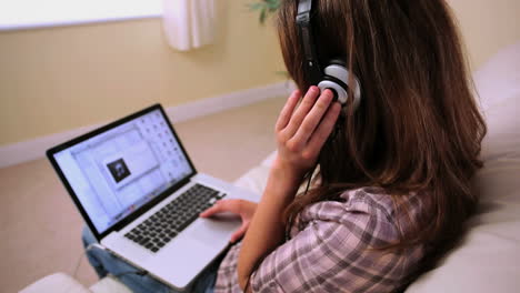 Content-attractive-brunette-sitting-on-couch-listening-to-music