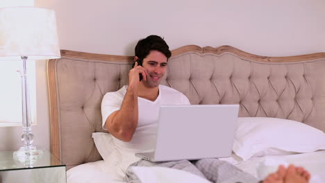 Happy-handsome-man-working-in-bed