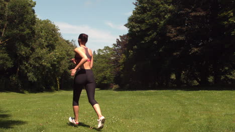 Vista-Trasera-De-Una-Mujer-Deportiva-Corriendo-Sobre-El-Césped.