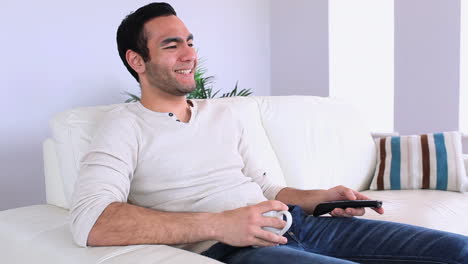 Handsome-man-watching-television-relaxing-on-his-sofa