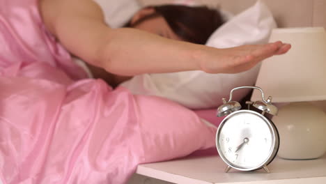 Irritated-young-woman-throwing-her-ringing-alarm-clock