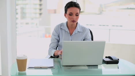 Exhausted-businesswoman-waking-up-from-a-nap-at-her-desk