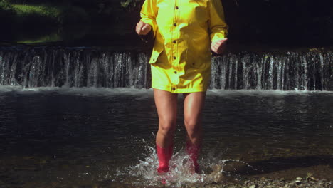 Woman-wearing-pink-rubber-boots-splashing-in-water