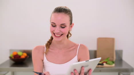 Smiling-model-shopping-online-with-her-tablet-pc