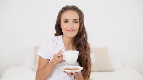 Young-woman-drinking-a-cup-of-tea-with-cookies