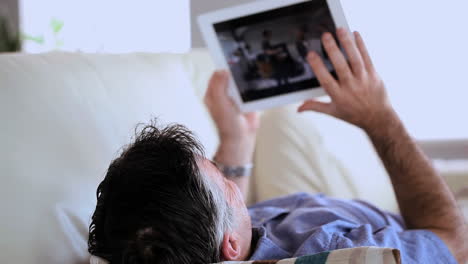 Reifer-Mann-Liegt-Auf-Der-Couch-Mit-Tablet-PC