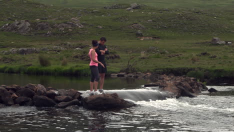 Couple-standing-on-rocks-in-the-middle-of-a-flowing-river
