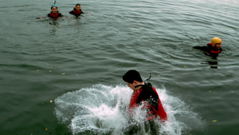 Man-in-wet-suit-doing-a-somersault-into-a-lake