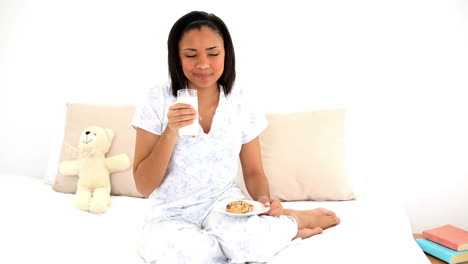 Cute-woman-sitting-on-her-bed-drinking-a-glass-of-water