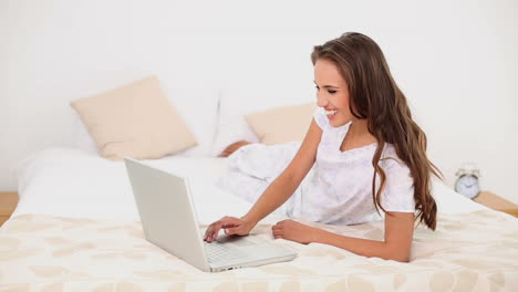 Junge-Frau-Mit-Ihrem-Laptop-Auf-Ihrem-Bett-Liegend