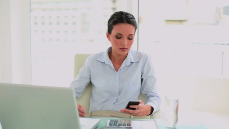 Pretty-businesswoman-texting-on-her-smartphone