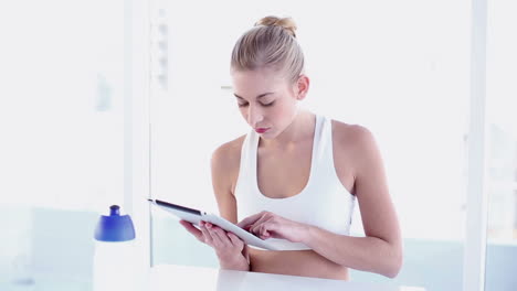 Sporty-smiling-blonde-using-tablet
