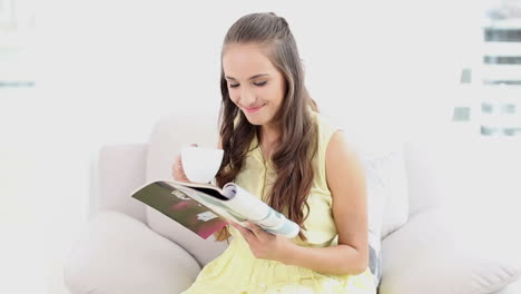 Young-woman-drinking-coffee-and-reading-a-magazine-on-the-couch