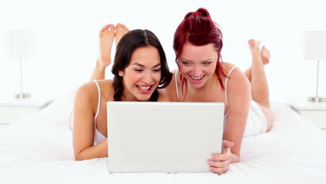 Beautiful-smiling-women-using-a-notebook-while-lying-on-bed