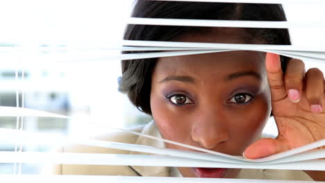 Businesswoman-looking-through-blinds