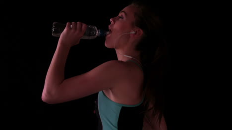 Woman-jogging-and-drinking-water-while-listening-to-music