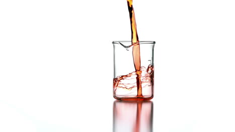 Orange-liquid-pouring-into-beaker