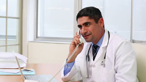 Doctor-sitting-at-desk-talking-on-the-phone