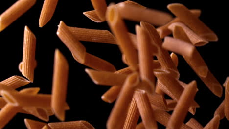 Penne-bouncing-against-black-background