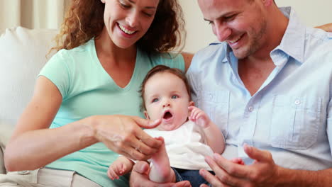 Young-happy-parents-sitting-on-the-couch-with-their-baby-son