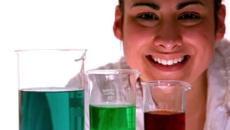 Scientist-smiling-at-the-camera-behind-beakers