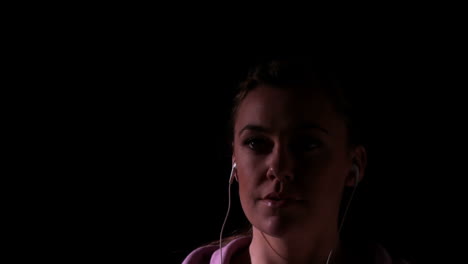 Woman-jogging-and-listening-to-music-against-black-background