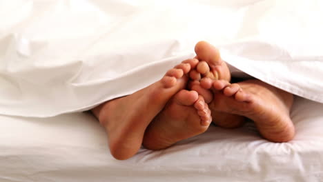 Die-Füße-Eines-Paares-Wackeln-Unter-Der-Bettdecke