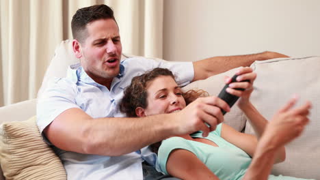 Happy-young-couple-relaxing-on-sofa-watching-tv