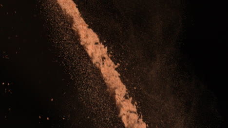 Brown-flour-falling-against-black-background