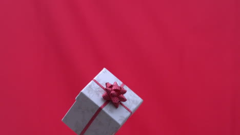 Weihnachtsgeschenk-In-Die-Luft-Geworfen-Auf-Rotem-Hintergrund