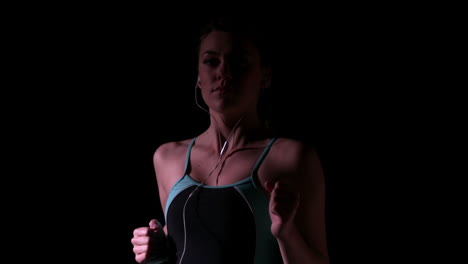 Woman-jogging-and-listening-to-music-against-black-background