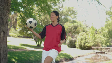 Niña-Asiática-Jugando-Al-Fútbol-En-El-Parque