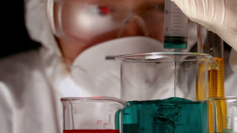 Scientist-mixing-and-pouring-liquid-into-beaker