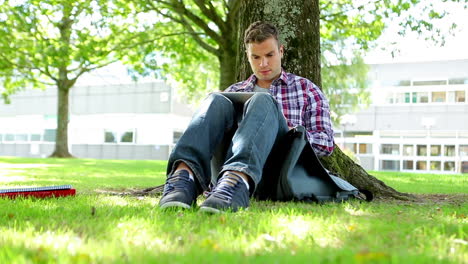 Young-student-sitting-on-the-grass-using-tablet-pc