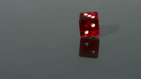 Red-dice-spinning-on-reflective-surface