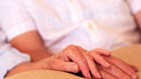 Senior-couple-sitting-on-couch-holding-hands