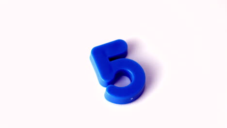 Number-five-falling-onto-white-surface