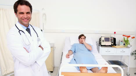 Sick-man-lying-on-hospital-bed-coughing-with-doctor-smiling-at-camera