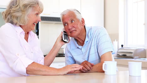 Senior-couple-sitting-at-counter-on-the-phone