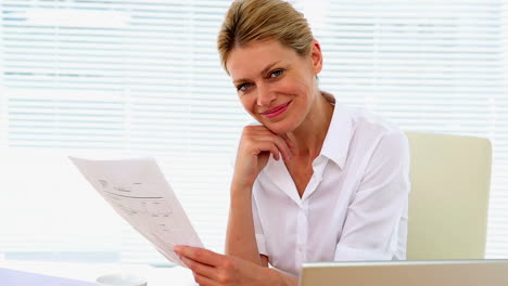 Businesswoman-reading-a-document-at-her-desk
