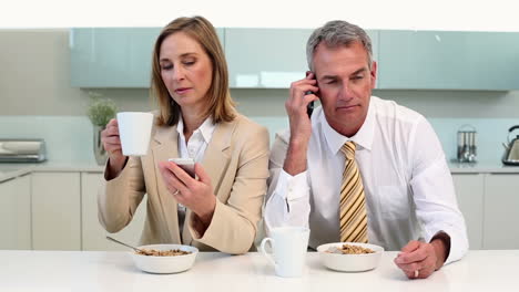 Couple-having-breakfast-and-using-phones-before-work-