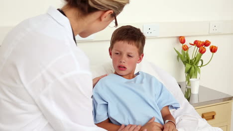 Little-sick-boy-sitting-in-bed-talking-with-doctor