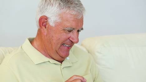 Senior-man-sitting-on-sofa-using-tablet