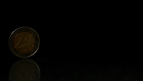 Euro-coin-rolling-over-black-surface