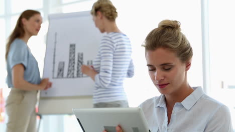 Mujer-De-Negocios-Usando-Tableta-Con-Colegas-Detrás-De-Ella