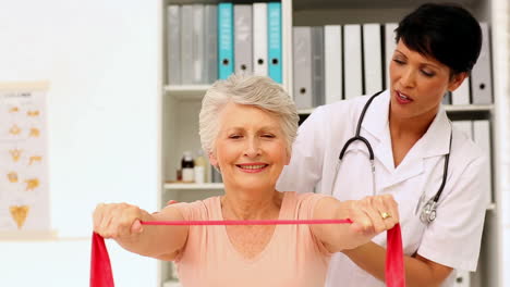 Enfermera-Mostrando-A-Un-Paciente-Anciano-Cómo-Usar-Una-Banda-De-Resistencia